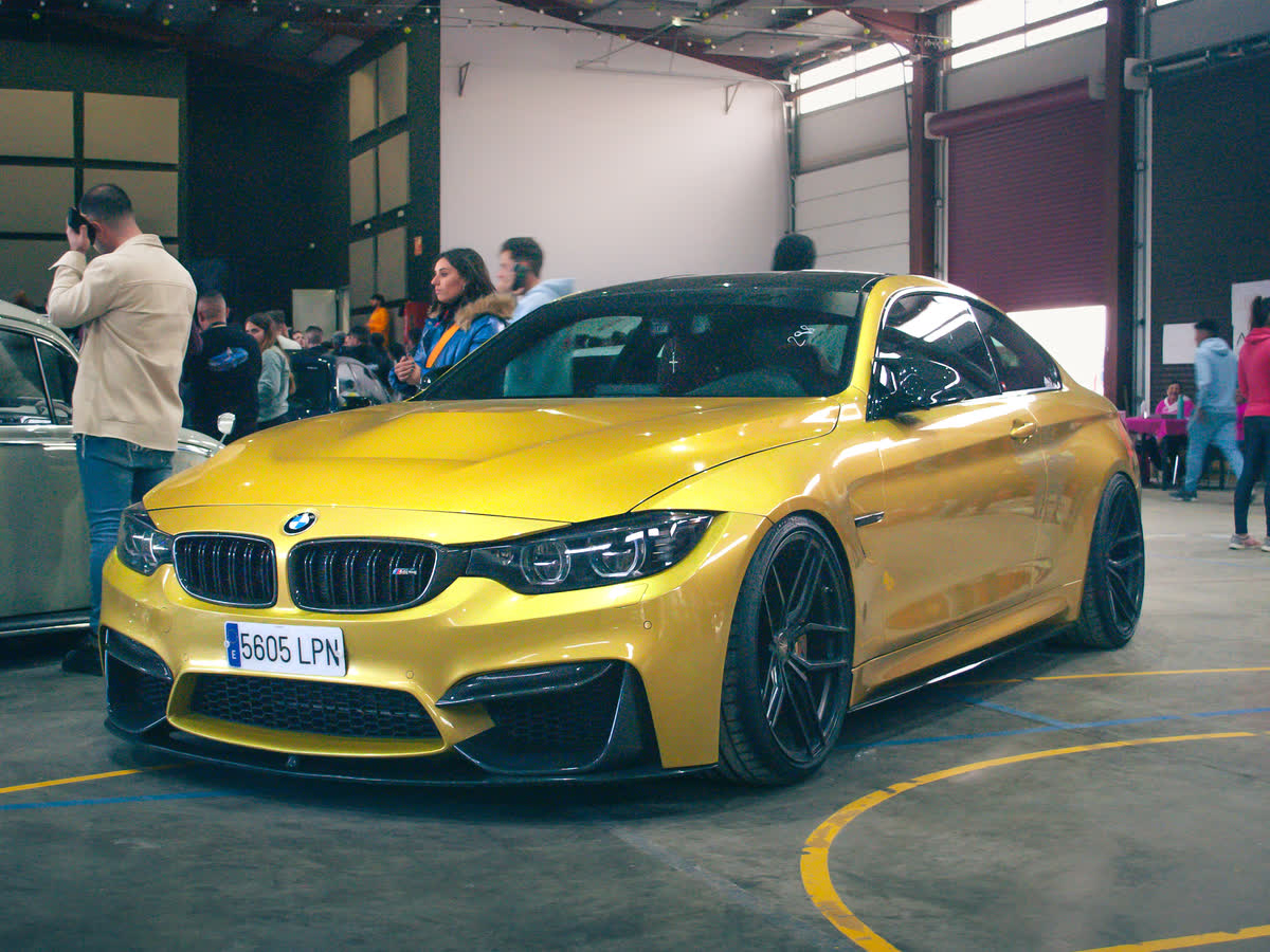 Aficionados de OC Drive junto a un BMW M4 amarillo en una exhibición